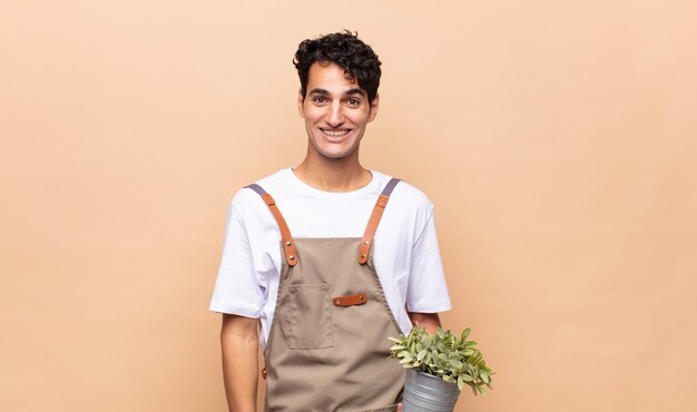 Homme jeune jardinier à la recherche de plaisir et agréablement surpris, excité par une expression fascinée et choquée