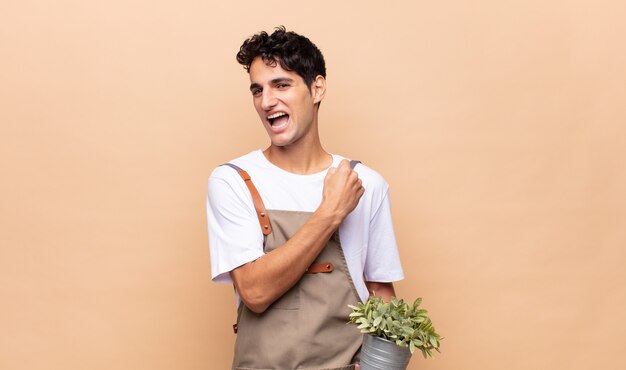 Homme jeune jardinier se sentant heureux, positif et prospère, motivé face à un défi ou célébrant de bons résultats