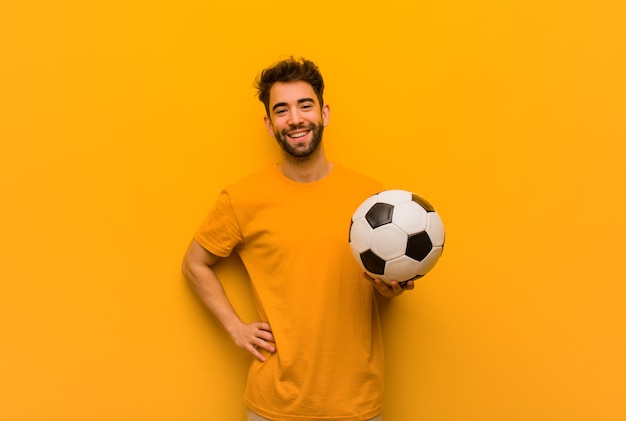 Homme jeune joueur de football avec les mains sur les hanches