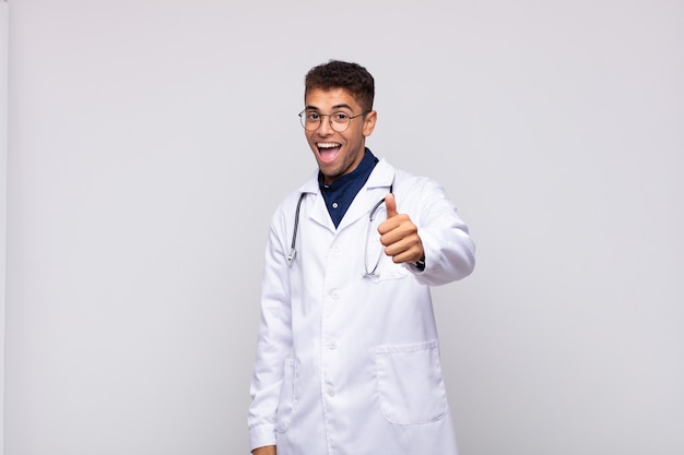 Homme jeune médecin se sentir fier, insouciant, confiant et heureux, souriant positivement avec les pouces vers le haut