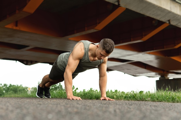 Un homme jeune et musclé fait des pompes pendant un entraînement de gymnastique suédoise dans une rue