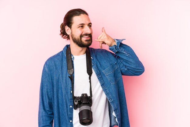 Homme jeune photographe caucasien isolé montrant un geste d'appel de téléphone mobile avec les doigts.