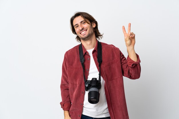 Homme jeune photographe isolé sur blanc souriant et montrant le signe de la victoire