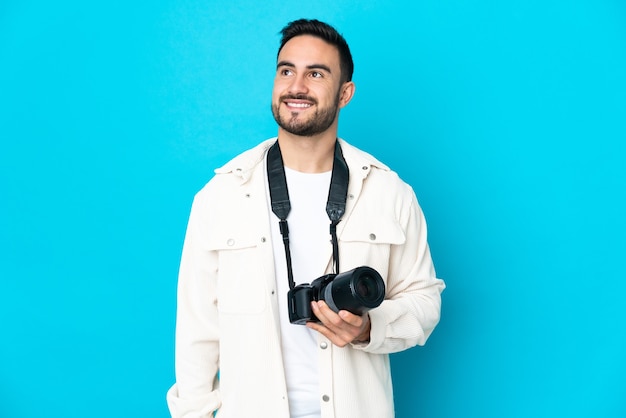 Homme jeune photographe isolé sur fond bleu en pensant à une idée tout en levant les yeux