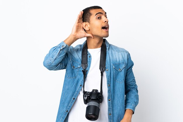 Homme jeune photographe sur mur blanc isolé écoutant quelque chose