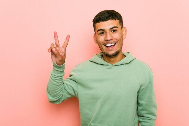 Homme Jeune Sport Hispanique Montrant Le Signe De La Victoire Et Souriant Largement.