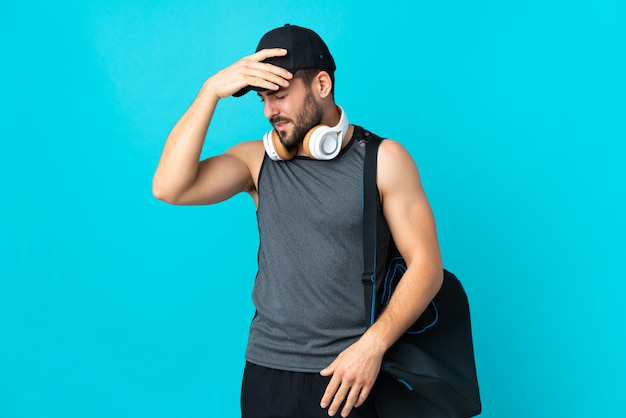 Homme Jeune Sport Avec Sac De Sport Isolé Sur Mur Bleu Avec Maux De Tête