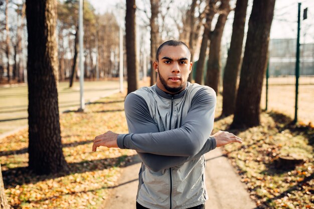 Homme jogger sur entraînement de remise en forme dans le parc de l'automne. Coureur en tenue de sport sur l'entraînement en plein air. Sportif s'échauffant avant de courir