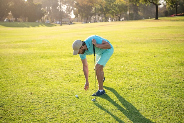 Homme jouant au jeu sur l'herbe verte prenant le ballon activité estivale sport professionnel joueur de golf masculin en plein air sur le parcours de golf professionnel portrait de golfeur en casquette avec style de vie des gens du club de golf