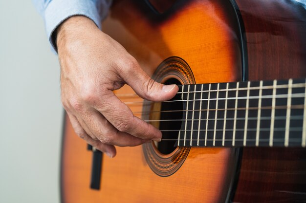 Homme jouant des cordes de guitare. Pratiquer et apprendre avec un cours en ligne