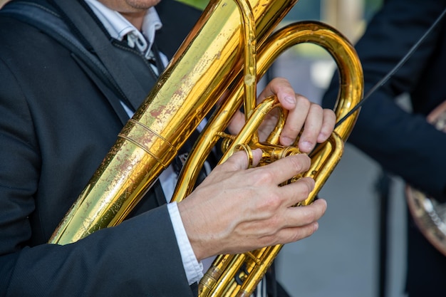 Photo homme jouant du tuba en laiton dans un groupe de musique de rue se produisant lors d'un festival en plein air