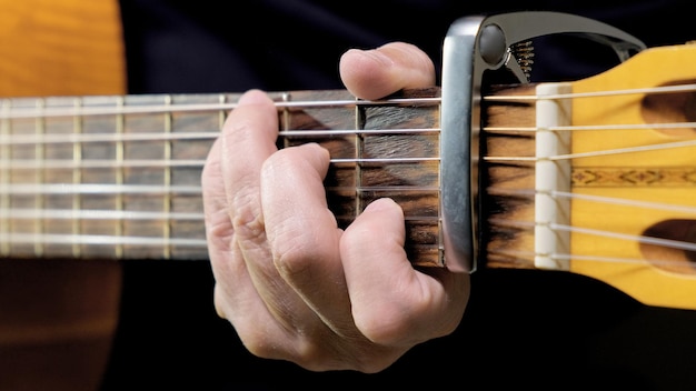 Un homme jouant de la guitare acoustique en gros plan et vue de face