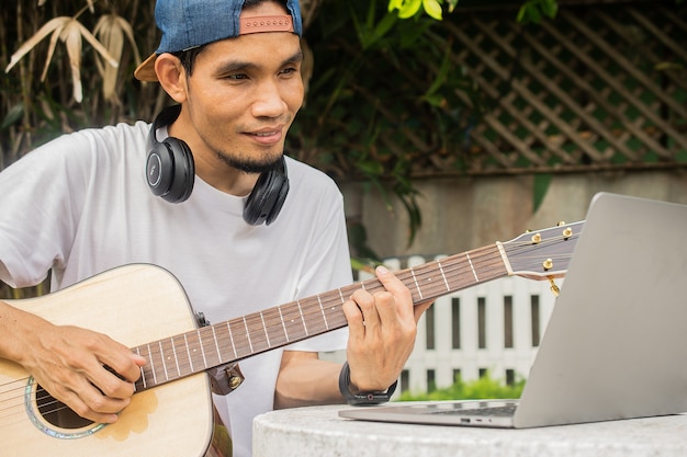 Homme jouant de la guitare et apprenant des cours de guitare en ligne