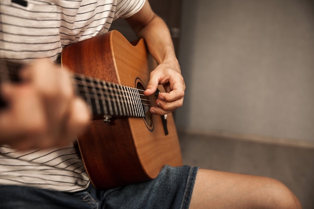 Homme jouant de la guitare à la maison, gros plan photo des mains