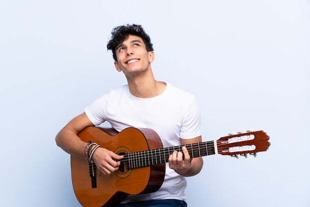 Homme jouant de la guitare sur un mur isolé