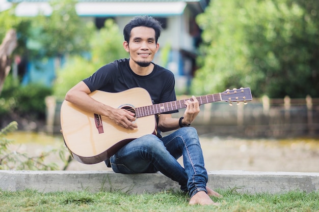 Homme jouant de la guitare en plein air heureux en été