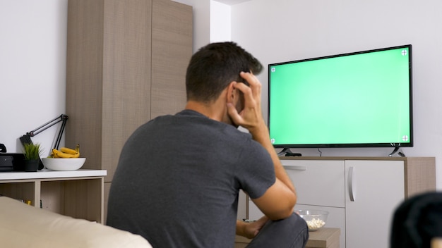 Homme jouant avec le joystick alors qu'il était assis dans son canapé. Temps de repos