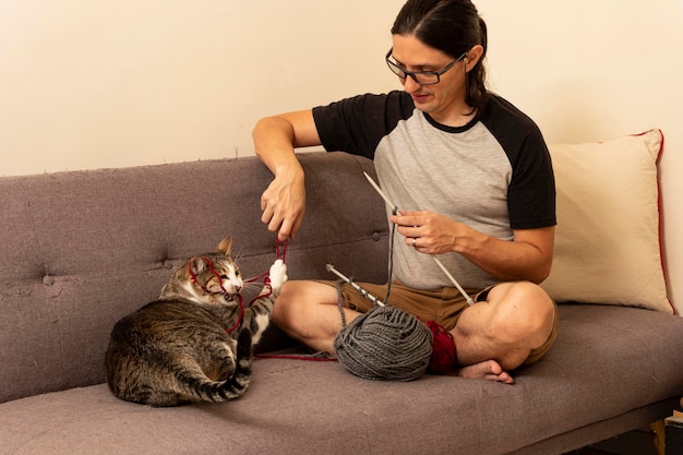 Homme jouant avec son chat sur le canapé à la maison