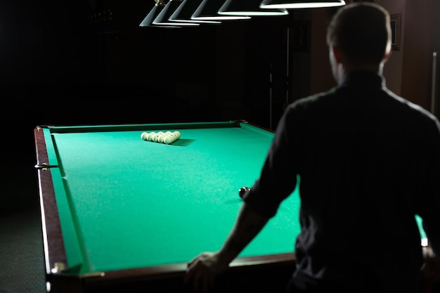 Un homme joue au billard. La vue de l'arrière