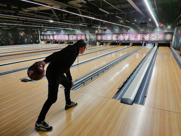Un homme joue au bowling lance une boule dans les quilles Vue arrière en perspective