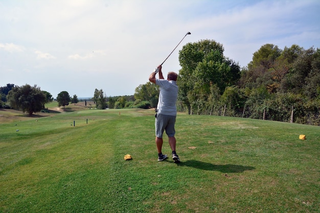 Un homme joue au golf sur un magnifique parcours de golf verdoyant et ensoleillé Frappe la balle de golf au loin