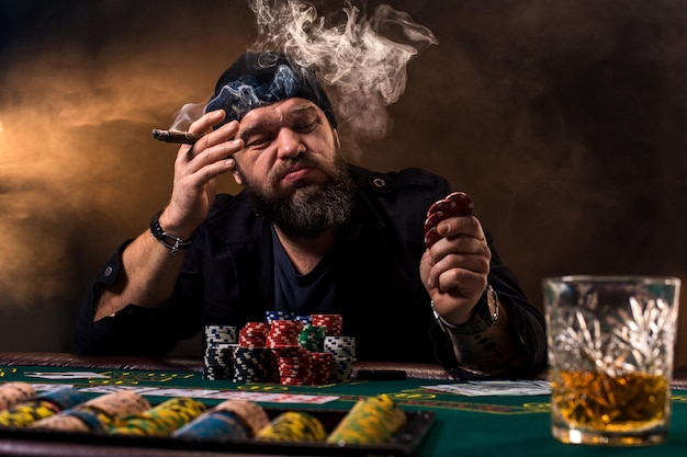 L'homme joue au poker avec un cigare et un whisky un homme gagne tous les jetons sur la table avec d'épais ...