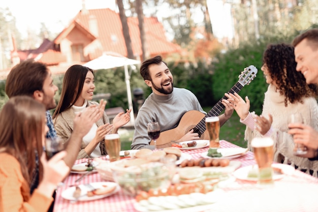 Un homme joue de la guitare lors d'un pique-nique avec des amis.