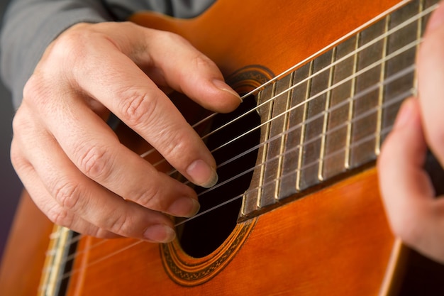 L'homme joue de l'instrument de musique à cordes de guitare classique mains du musicien jouant à la guitare classique