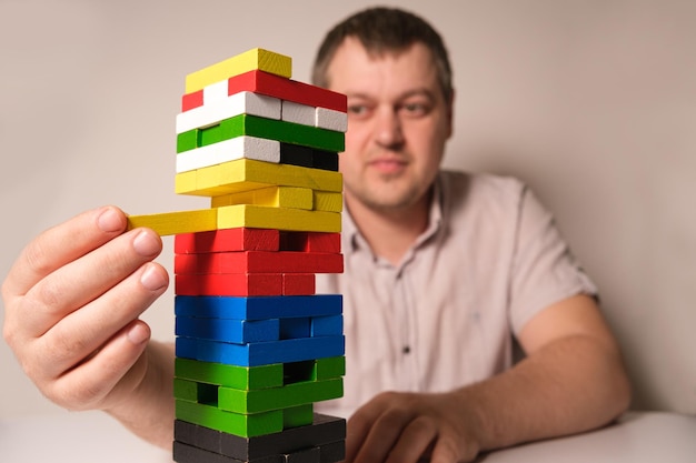 Un homme joue à un jeu de société et retire soigneusement des blocs de la tour