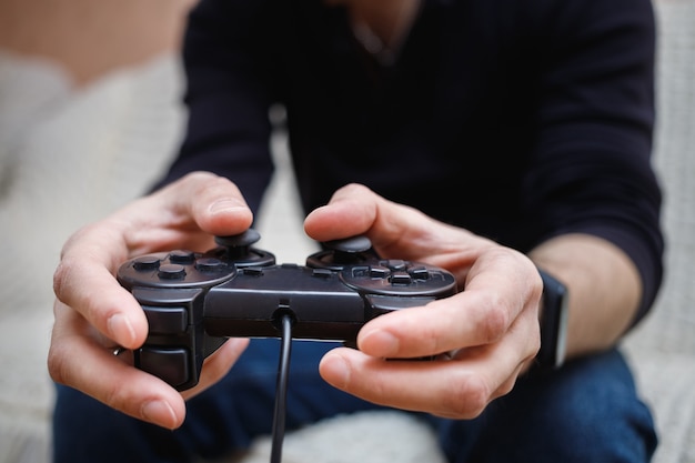 Un homme joue à des jeux vidéo avec un joystick dans ses mains