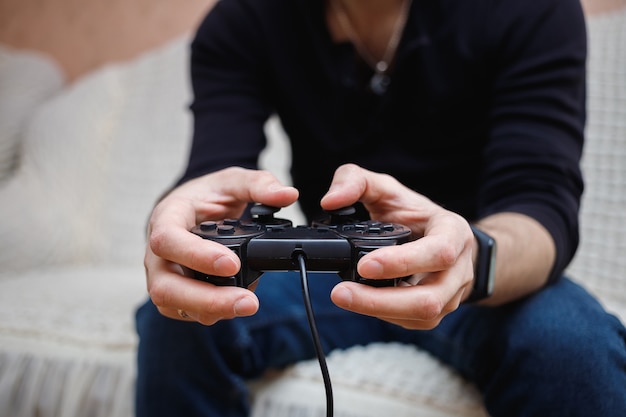 Un homme joue à des jeux vidéo avec un joystick dans ses mains