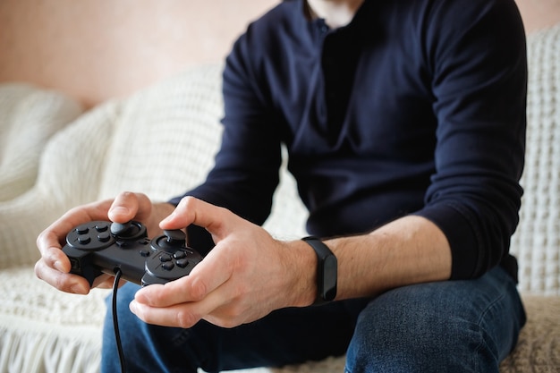 Un homme joue à des jeux vidéo avec un joystick dans ses mains