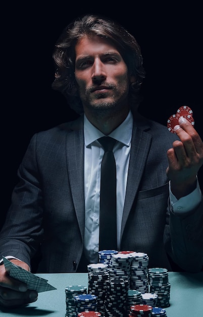 Homme joueur au casino assis à table avec des cartes et des jetons de poker
