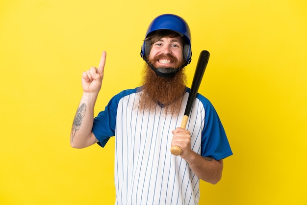 Homme de joueur de baseball rousse avec casque et batte isolé sur fond jaune pointant vers une excellente idée