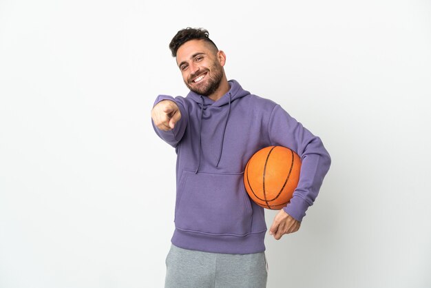 Homme de joueur de basket-ball isolé sur fond blanc pointant vers l'avant avec une expression heureuse