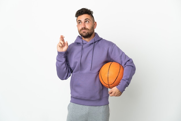 Homme de joueur de basket-ball isolé sur un mur blanc avec les doigts qui se croisent et souhaitant le meilleur