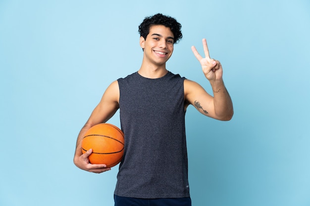 Homme joueur de basket-ball vénézuélien sur isolé souriant et montrant le signe de la victoire