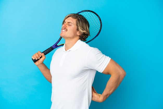 Homme de joueur de tennis blonde isolé sur mur bleu souffrant de maux de dos pour avoir fait un effort