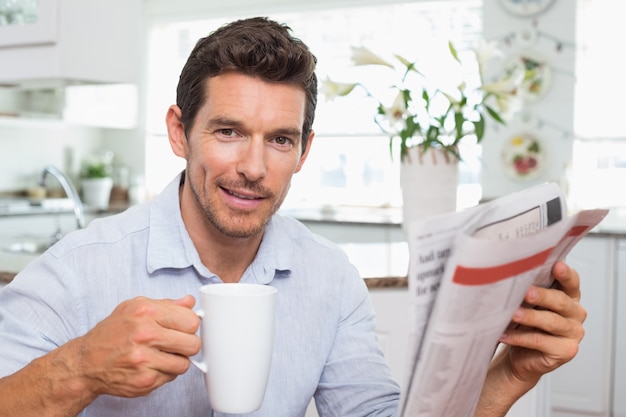 Homme avec journal et tasse de café à la maison