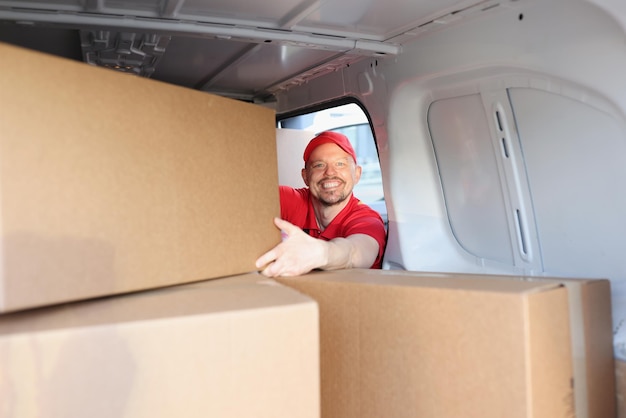 Un homme joyeux au travail a mis des boîtes dans un camion pour une livraison ultérieure à l'adresse