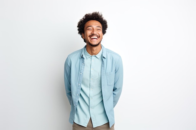 Un homme joyeux aux cheveux bouclés portant une chemise bleue sourit à la caméra