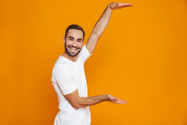 Homme joyeux avec barbe et moustache montrant la taille de copyspace en position debout, isolé sur jaune