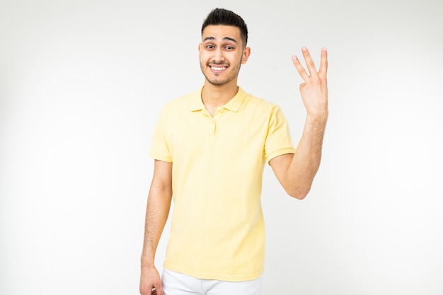 Homme joyeux dans une chemise jaune montre trois doigts sur un blanc isolé