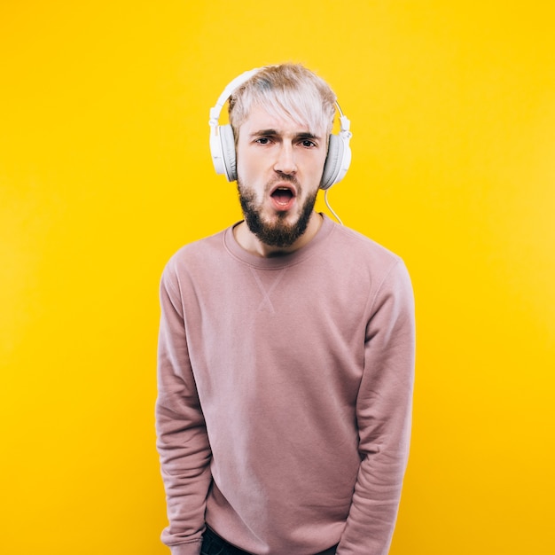 Homme joyeux écoutant de la musique sur des écouteurs sur fond jaune