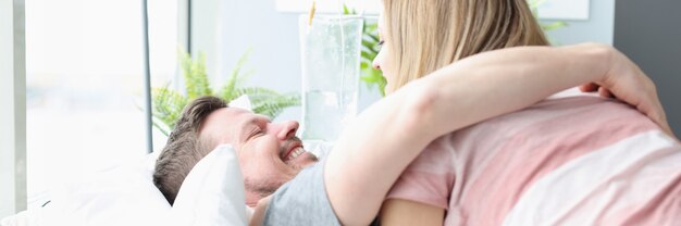 Un homme joyeux embrasse une femme sur un lit d'hôpital pour une récupération rapide du concept de maladie