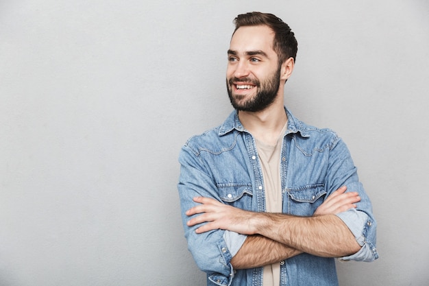 Homme joyeux excité portant une chemise isolée sur un mur gris, les bras croisés