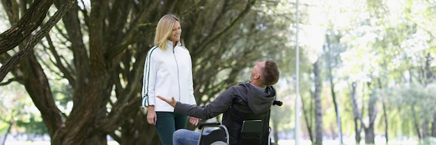 Un homme joyeux en fauteuil roulant rencontre une femme dans un parc rencontrant des amis dans un concept de parc