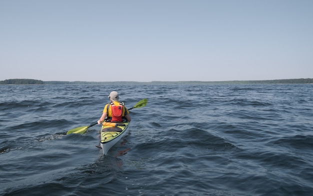 Un homme sur un kayak glisse à la surface de l'eau. Thème des sports nautiques