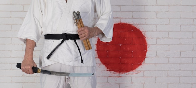 homme en kimono blanc avec des nunchucks