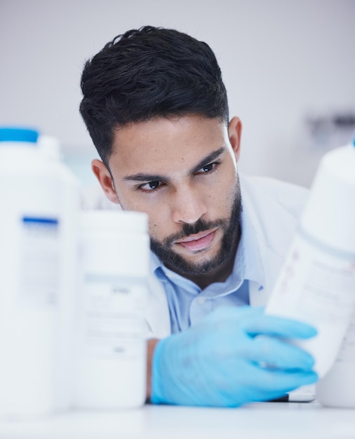 Homme de laboratoire ou scientifique lisant une bouteille pour vérifier le stock médical ou des informations sur la percée de la guérison Étiquette de conteneur d'étude de recherche ou chercheur scientifique dans un travail de fabrication avec inventaire chimique